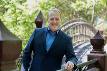 Doug Schmidt leans on a railing while standing on a bridge.